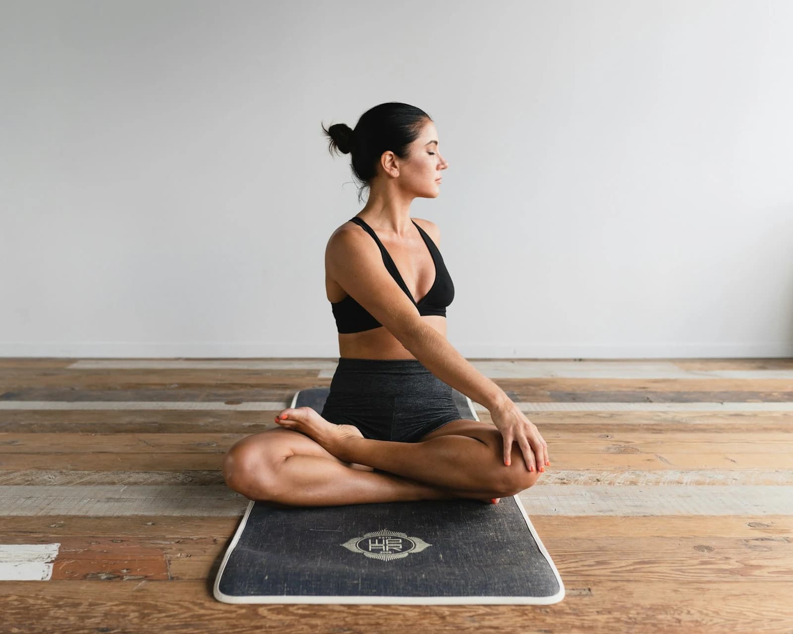 Nordic Fitness gym member holding a seated twist on a mat, on a timber floor in soft daylight